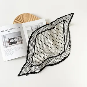 Close-up detail of a white pleated square scarf with black polka dots and stripes