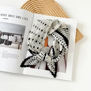 Close-up detail of a white and black polka dot pleated silk scarf on a magazine