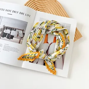 Detailed view of a stylish pleated satin scarf with bright lemon prints on an open magazine