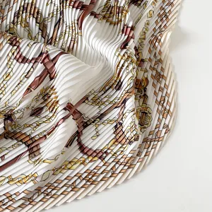 Detailed close-up of a pleated satin scarf featuring an elegant chain and belt pattern print.