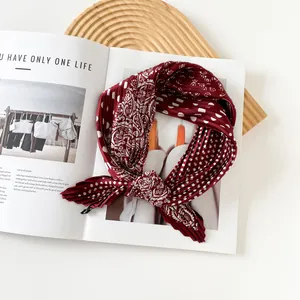 Detailed view of red pleated square silk scarf with paisley and polka dot pattern