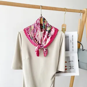 Detailed view of elegant pink floral pleated silk square scarf styled on a dress collar