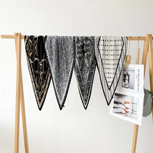 Close-up of four printed pleated silk scarves hanging on a wooden rack