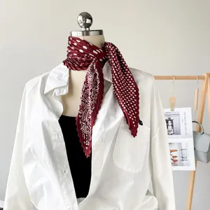 Elegant burgundy pleated silk scarf with white dots and floral print styled on a mannequin.