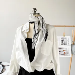 Detail view of a pleated black and white printed satin scarf styled on a mannequin.