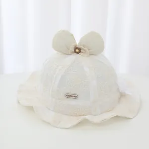 Close-up detail of a white baby lace fisherman hat featuring a bow and floral embroidery