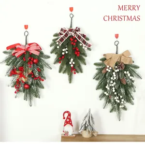 Three artificial Christmas teardrop swags with berries and pinecones on a white wall