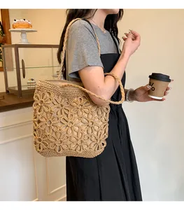 Casual straw woven tote bag with flower hollow pattern shown on shoulder