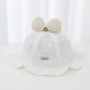 Detailed close-up of a white baby girl lace bucket hat featuring a large butterfly bow