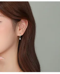 Detail of a gold-plated silver earring with a pear-shaped opal and cubic zirconia