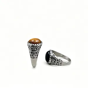 Close-up of vintage engraved patterns on men's stainless steel rings with tiger's eye