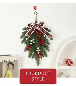 Christmas swag decoration with pine needles, red berries and plaid bow hanging on wall.