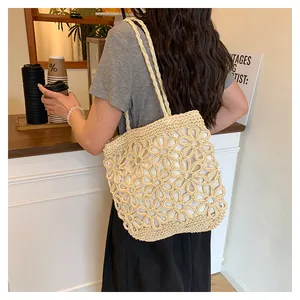 Detailed view of a beige straw woven tote bag with flower cutout patterns on shoulder.