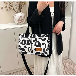 Detail showing a large leopard print tote bag with black handles and shoulder strap