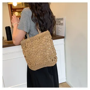 Detail view of a woven straw tote bag with an intricate floral hollow-out design