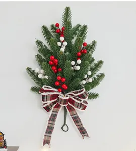 Detail of Christmas wall hanging swag with pine needles, berries and plaid bow.
