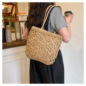Exquisite hand-woven hollow floral straw tote bag shown in a lifestyle cafe setting