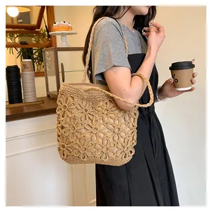 Detail shot of hand-woven hollow floral straw tote bag carried in a cafe setting.