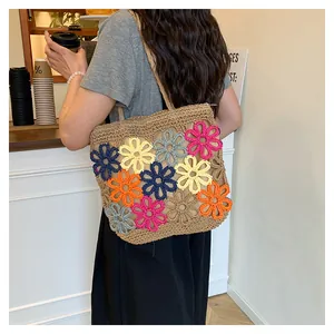 Detailed view of a handmade hollow woven straw tote bag with vibrant crochet flowers