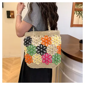 Detail of a woven straw tote bag featuring multi-colored hollow flower patterns.