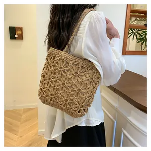 Hand-woven floral hollow-out tote bag carried by a woman in a boutique setting