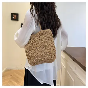 Detail view of a woven floral hollow-out tote bag shown on a female model's shoulder.