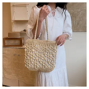 Detail view of a beige woven straw tote bag with elegant floral hollow-out patterns.