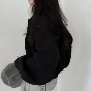 Detail of black corduroy cropped jacket with drawstring hem and minimalist design.