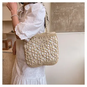 Detail view of a handmade woven straw tote bag featuring a floral hollow-out design