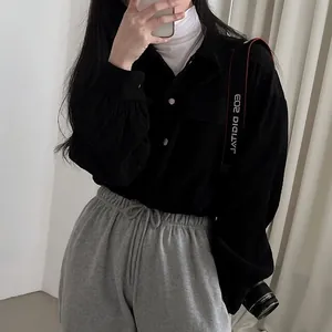 Close-up of a chic black corduroy long-sleeve shirt styled with grey sweatpants