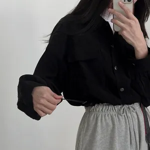 Detail view of a black corduroy cropped jacket featuring a drawstring hem and silver buttons