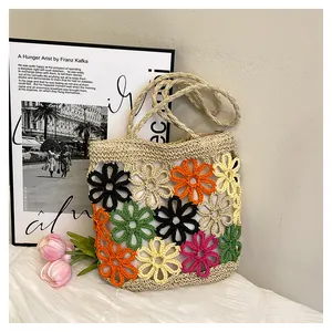 Detailed view of a handmade woven straw tote bag featuring colorful hollow flower patterns