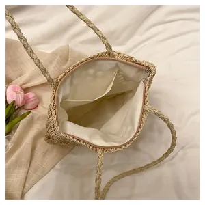 Interior detail of large woven straw tote bag showing beige fabric lining and side pocket