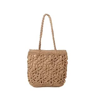 Handcrafted woven straw tote bag with elegant hollow flower pattern for summer beach.