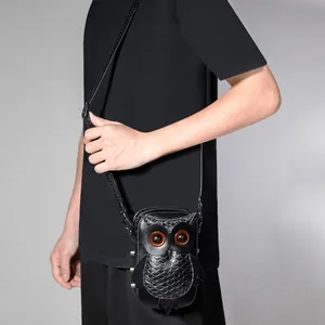 Punk style owl-shaped small crossbody bag in black faux leather carried by a model