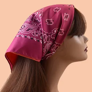 Detailansicht eines magenta Paisley-Viereck-Bandanas, als Kopftuch getragen