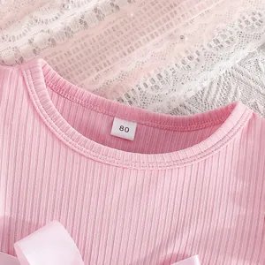 Close-up of pink ribbed baby dress neckline with size 80 tag and delicate lace detail