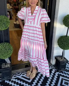 Woman wearing a pink and white striped tiered maxi dress in a sunny outdoor setting