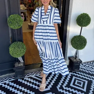 Summer blue and white striped tiered maxi dress featuring puff sleeves and pom-pom V-neck.