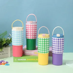 Four colorful 30oz checkered tumblers with handles arranged on decorative prop books.
