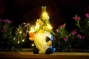 Close-up of solar garden gnome with glowing LED flowers in a night garden setting