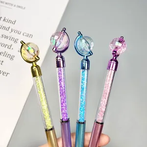 Four colorful crystal ballpoint pens with globe tops held in hand