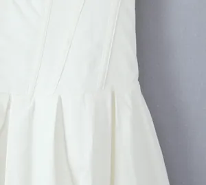 Close-up detail of a white pleated A-line dress showing the waist and stitching