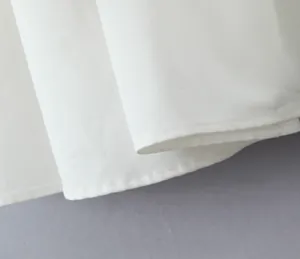 Close-up of high-quality white fabric and fine stitching detail on a summer dress hem.