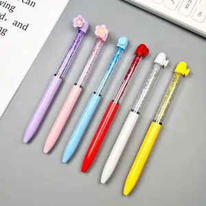 Colorful crystal ballpoint pens set with floral caps on a clean office desk background.
