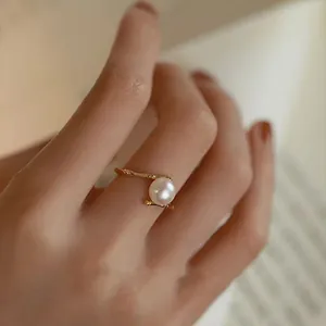 Detailed macro view of an elegant pearl ring with a golden bamboo-style adjustable band