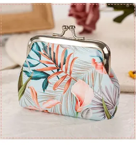 Detailed view of the tropical palm leaf print on a silver kiss-lock coin purse