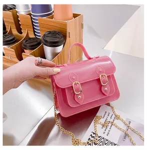 Detail view of hot pink jelly satchel bag with golden buckles and chain strap