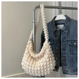 Large cream bubble cloud shoulder bag displayed on a garment rack next to a denim jacket.