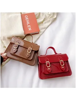 Close-up detail of glossy jelly Cambridge handbags in brown and red on white ribbed fabric